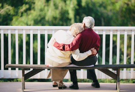 two elderly people hugging on a bench