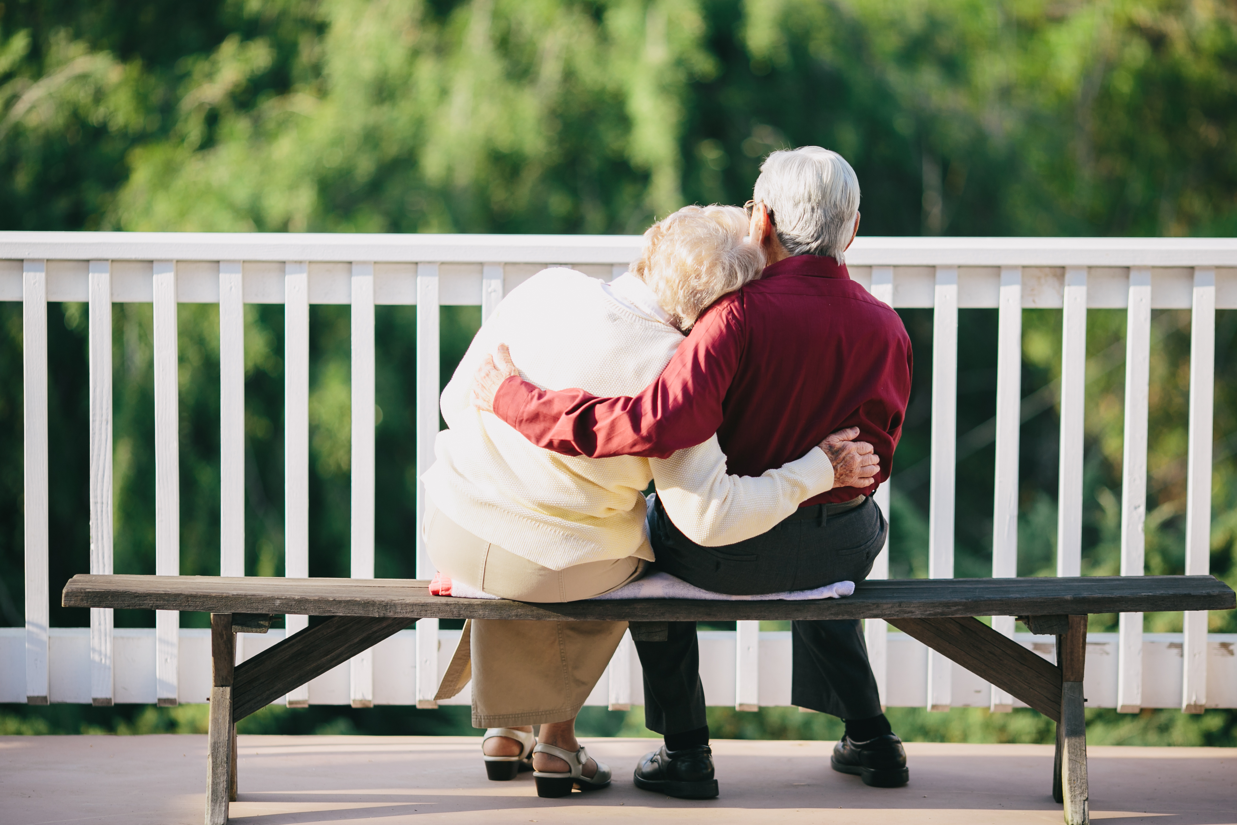 two elderly people hugging on a bench