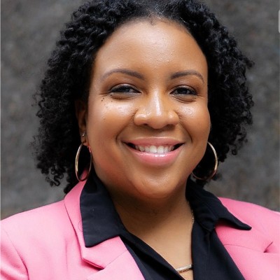 African American woman smiling for headshot, wearing pink blazer