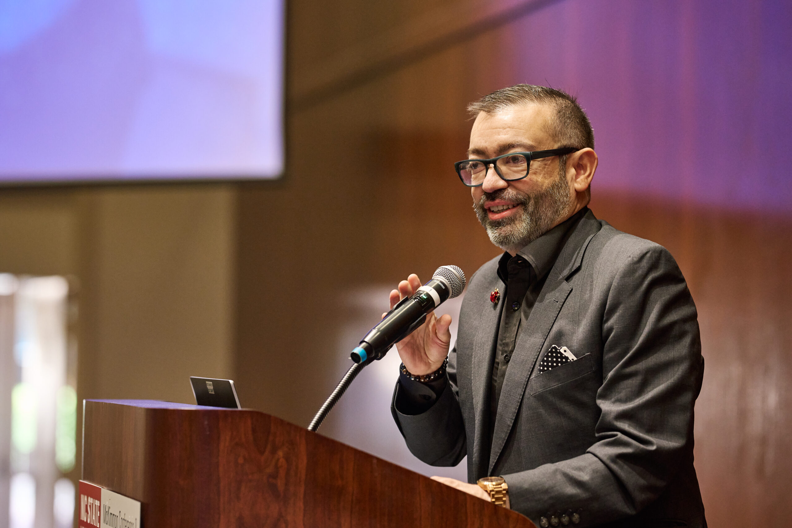 image of Robert Espinoza giving keynote speech behind wooden podium at NCIOM annual meeting