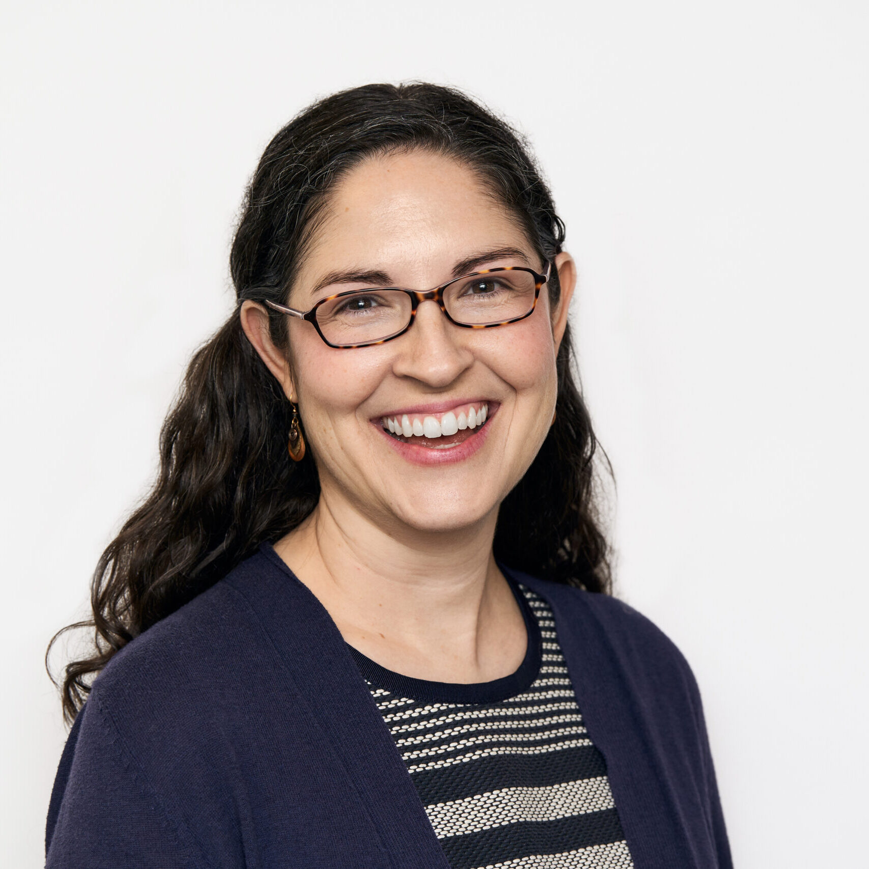 Headshot of a smiling woman with dark hair wearing a blue-striped top and blue cardigan